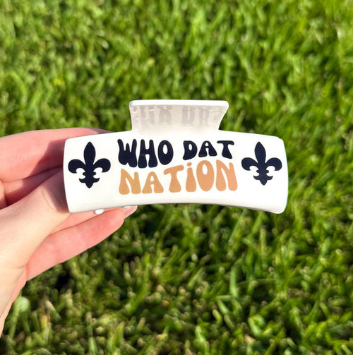 White hair claw clip with black and gold Who Dat Nation text and fleur de lis symbols