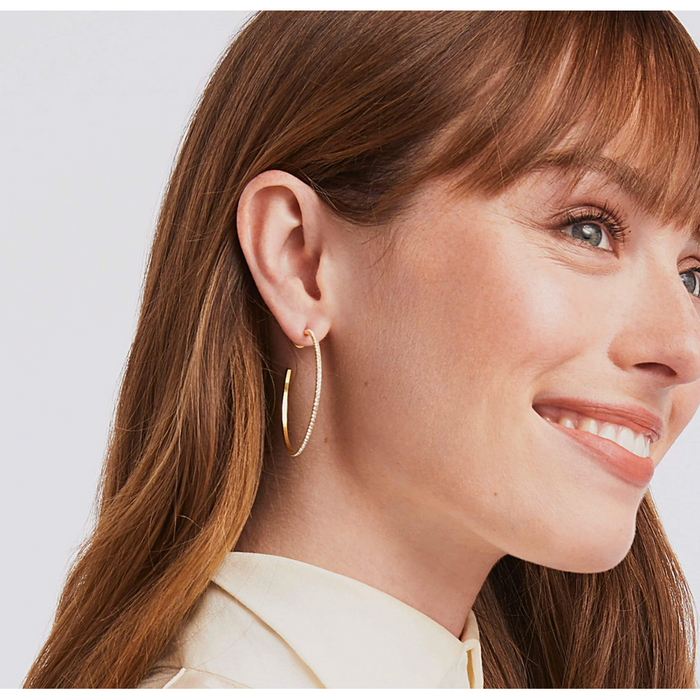Woman wearing a gold hoop earring with small embedded stones
